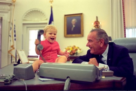 President Lyndon B. Johnson watches his grandson play with the telephone