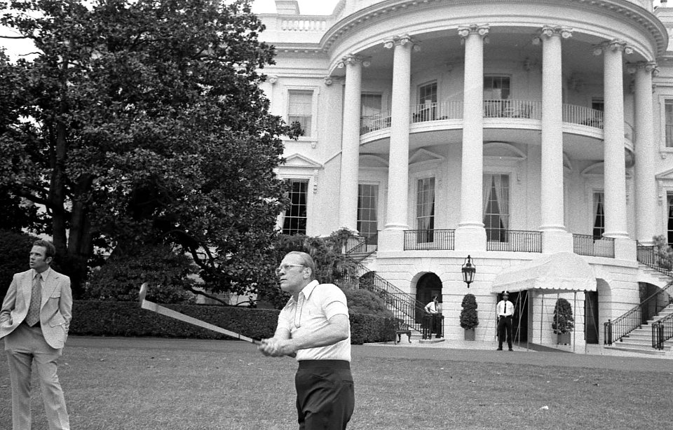 President Gerald Ford practices golf under the watchful eye of the Secret Service