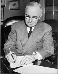 President Harry S. Truman is shown at his desk at the White House signing a proclamation declaring a national... - NARA - 541951 photo