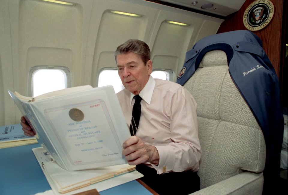 President Ronald Reagan aboard Air Force One reading Summit notes during trip to to Finland and Moscow Summit