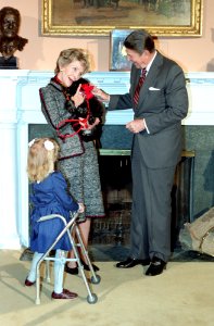 President Ronald Reagan and Nancy Reagan holding a dog meeting with 1985 March of Dimes Poster Child Kristen Ellis