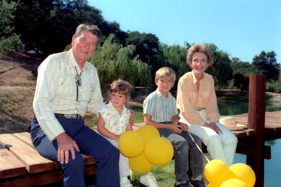 President Ronald Reagan and Nancy Reagan sitting on the dock with their grandchildren Cameron Reagan and Ashley Marie Reagan
