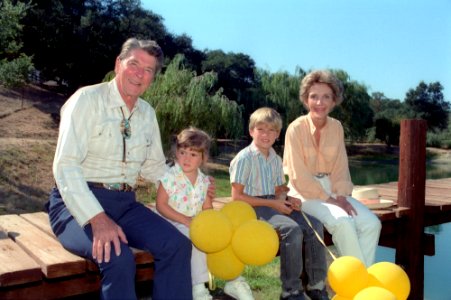 President Ronald Reagan and Nancy Reagan sitting on the dock with their grandchildren Cameron Reagan and Ashley Marie Reagan