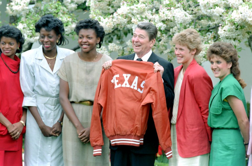 President Ronald Reagan holds up a Texas jacket while meeting with NCAA basketball women's champion from University of Texas in the Rose Garden