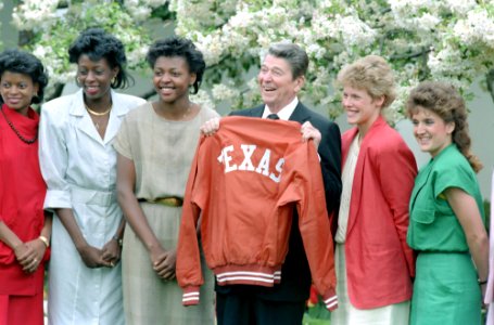 President Ronald Reagan holds up a Texas jacket while meeting with NCAA basketball women's champion from University of Texas in the Rose Garden