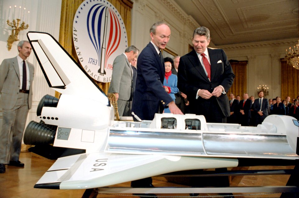 President Ronald Reagan participating in a ceremony commemorating the 200th anniversary of manned flight looking at model of the Space Shuttle in the East Room