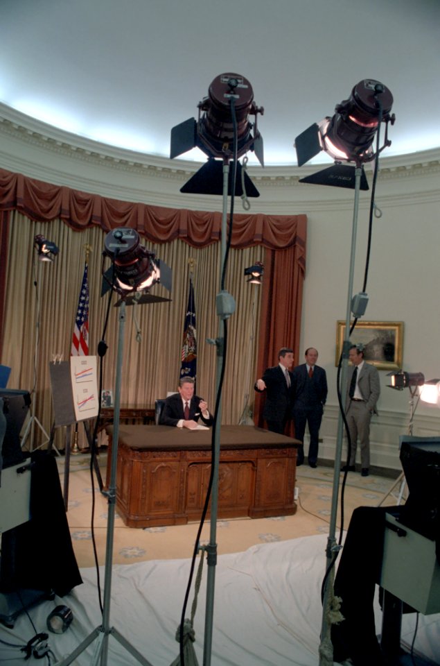 President Ronald Reagan preparing for Address to the Nation on the Economy in the Oval Office with television equipment with James Brady