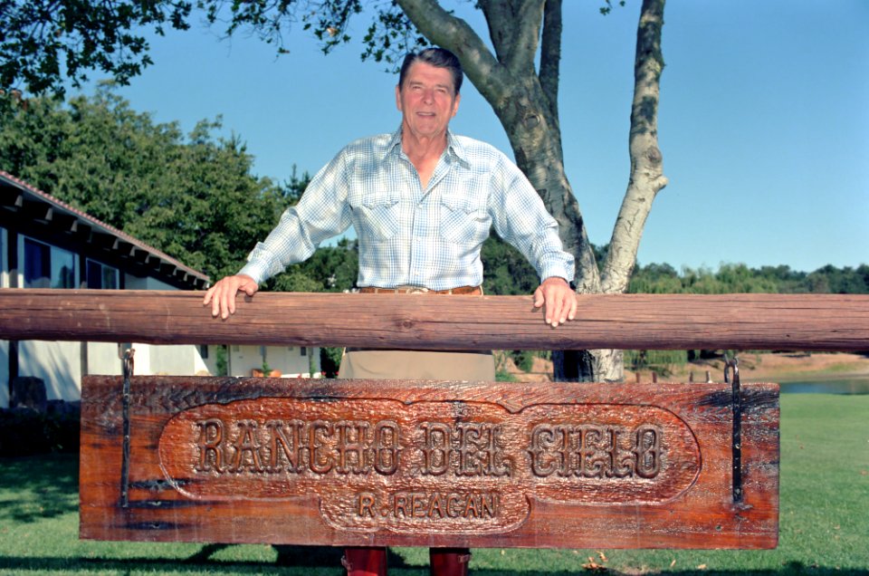 President Ronald Reagan standing above his ranch sign at Rancho Del Cielo