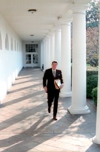President Ronald Reagan walking along colonnade carrying papers