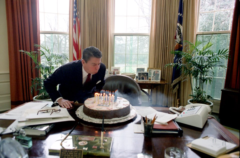 President Ronald Reagan Blowing out Candles on a Cake while Celebrating his Birthday Party in Oval Office
