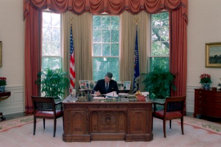 President Ronald Reagan working at his desk in the Oval Office photo