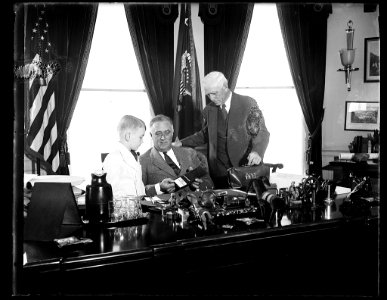 PRESIDENT ROOSEVELT IS READY FOR THE OPENING DAY OF THE BASEBALL SEASON TOMORROW AS CLARK GRIFFITH, PRESIDENT OF THE WASHINGTON CLUB, PRESENTS HIM WITH A GOLD PASS