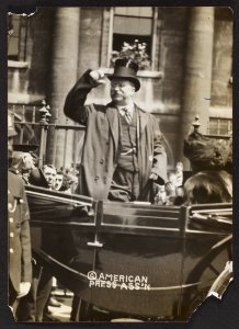 President Theodore Roosevelt standing in an open carriage looking out at spectators gathered to see him LCCN2013651468