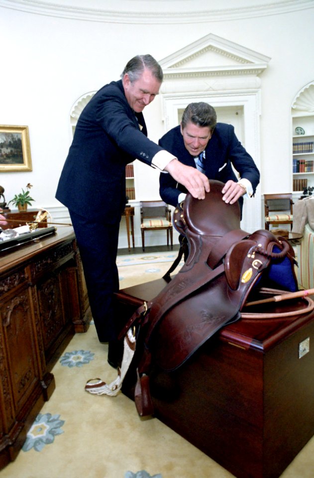 President Ronald Reagan looking at a saddle given to him by Prime Minister Malcolm Fraser of Australia in the Oval Office