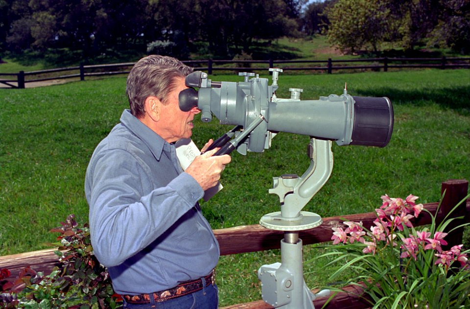 President Ronald Reagan looking through long range binoculars