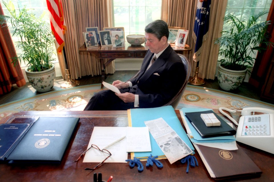 President Ronald Reagan reading in the Oval Office