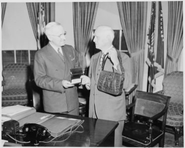President Truman, in the oval office, receives tickets to a baseball game and an alligator handbag for Mrs. Truman... - NARA - 199751 photo