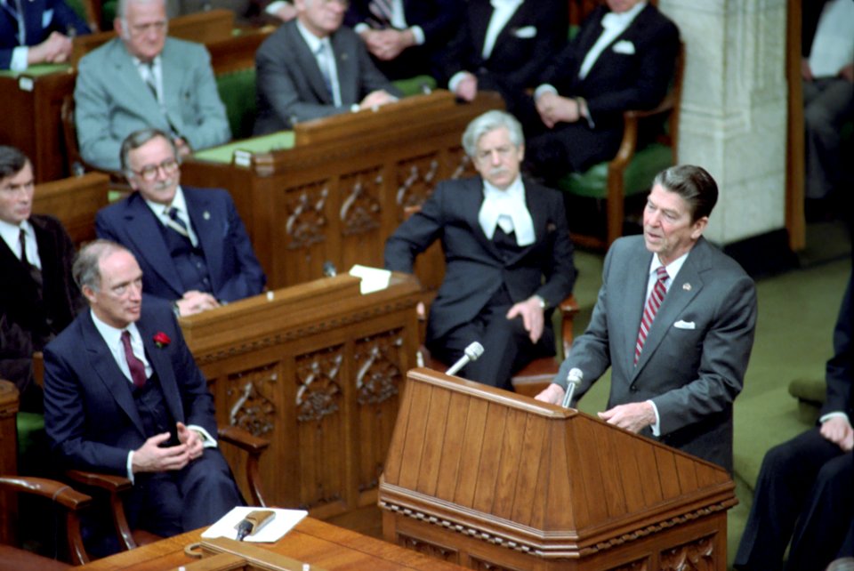 President Ronald Reagan speaking at podium while addressing members of the House of Commons during trip to Canada