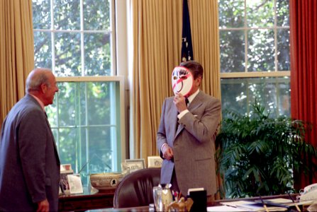 President Ronald Reagan wearing an Anti-Dukakis mask and showing George ShultZ in the Oval Office