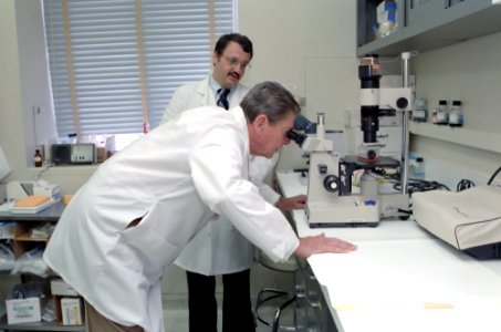 President Ronald Reagan looking in a microscope with Samuel Broder looking on during his visit to National Institutes of Health in Bethesda, Maryland
