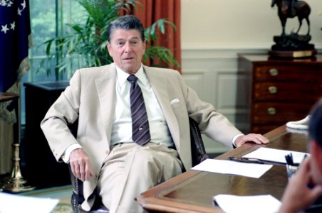 President Ronald Reagan sitting at desk in the Oval Office photo