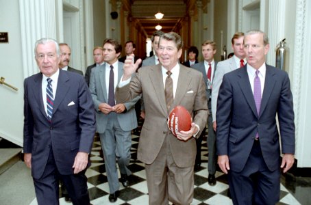 President Ronald Reagan walking back to the White House with Donald Regan and James Baker from the OEOB and holding a football