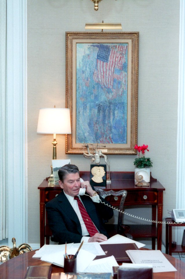 President Ronald Reagan working and talking on the telephone in the Oval Office study