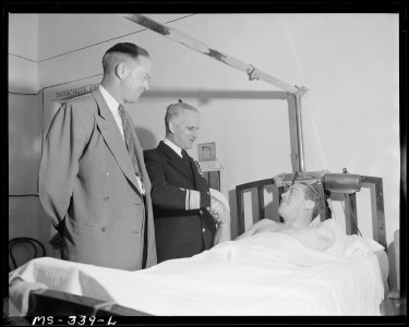 Rear Admiral Joel T. Boone shakes hands with Benny Phillips, miner, injured in shuttle car accident as Dr. R. L.... - NARA - 540365