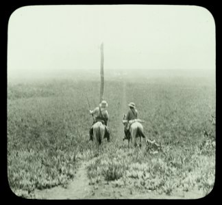 Rear view of Theodore Roosevelt and another man carrying guns on horses in Africa LCCN90707096