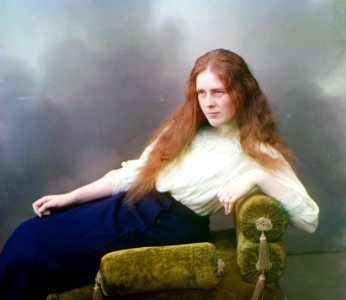 Reclining red-haired woman in white blouse and blue skirt (by Sergey Prokudin-Gorsky, ca. 1910)
