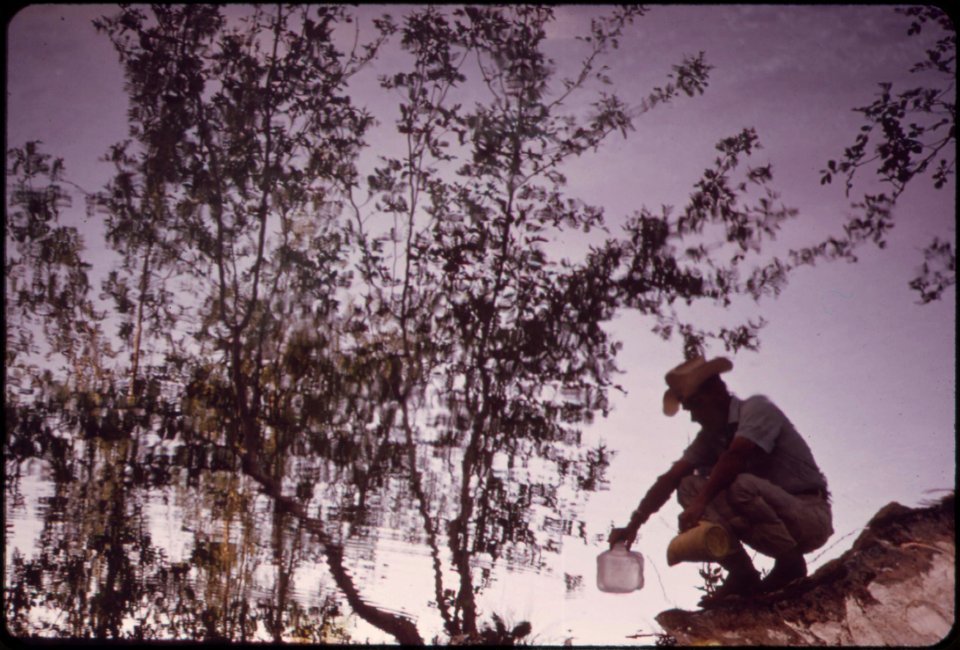 Reflected-image-of-epa-technician-collecting-water-sample-from-pahranagat-lake-about-10-miles-south-of-alamo-may-1972 7136417303 o