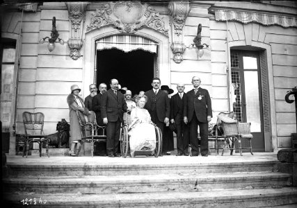 Remise de la légion d'honneur à M. Tuck (qui porte la décoration et pose sur le perron à droite, en compagnie de sa femme) Mme Tuck (en fauteuil roulant et de MM. Herriot et Bourguignon) - (photographie de presse) - (Agence Rol)