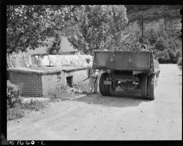 Removing garbage from house garbage disposal shelter. Garbage is then hauled by truck to remote mountain area.... - NARA - 540897