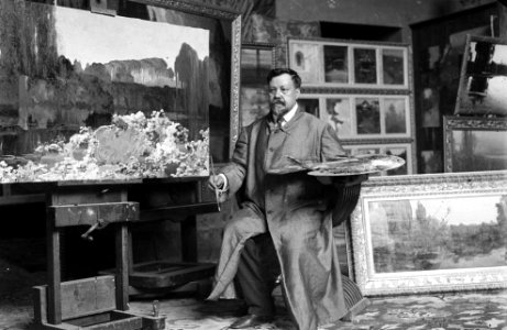 Retrat del pintor Enric Serra Auqué al seu estudi voltat de quadres (cropped)