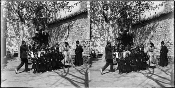 Retrat d'un grup de nenes mudades , dones i un home al costat de l'església de la Mare de Déu del Coll
