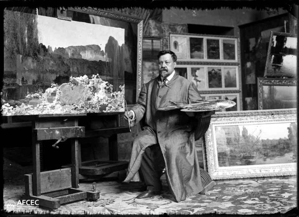 Retrat del pintor Enric Serra Auqué al seu estudi voltat de quadres