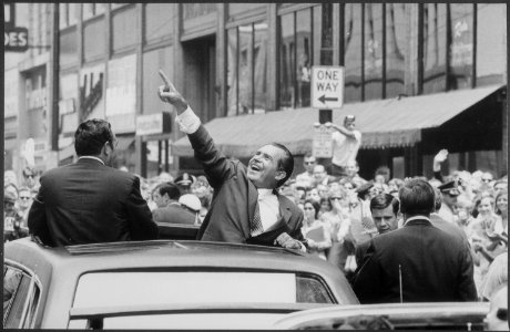 Richard M. Nixon pointing at the crowd from the roof of his car during a motorcade. - NARA - 194683 photo