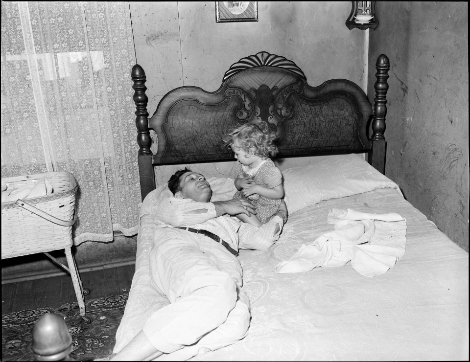 Richard Hughes, a miner, plays with his young daughter as he awakens from midday nap before going to work on the... - NARA - 541008