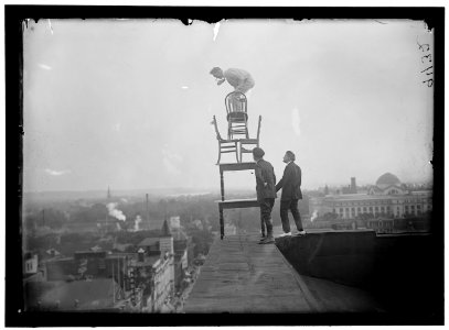 REYNOLDS, J., PERFORMING ACROBATIC AND BALANCING ACTS ON HIGH CORNICE ABOVE 9TH STREET, N.W. LCCN2016868362