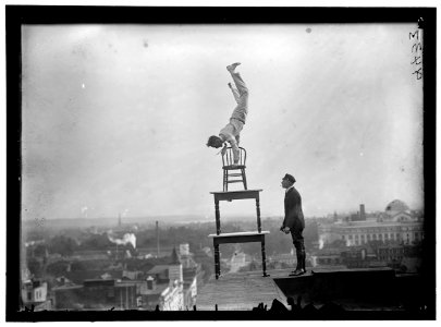 REYNOLDS, J., PERFORMING ACROBATIC AND BALANCING ACTS ON HIGH CORNICE ABOVE 9TH STREET, N.W. LCCN2016868363 photo