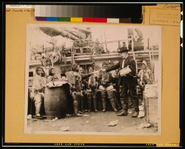 Robert Edwin Peary, full-length portrait, standing on deck of ship or dock, facing left, distributing gifts to Eskimos, Greenland LCCN00650164 photo