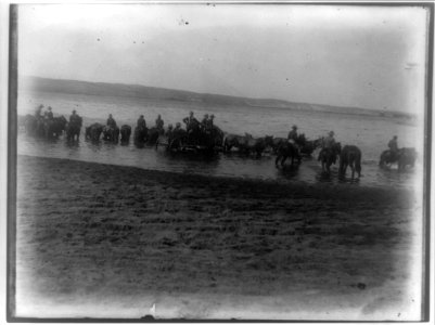 Rough riders on horseback in water with wagon at Montauk Point LCCN96503325