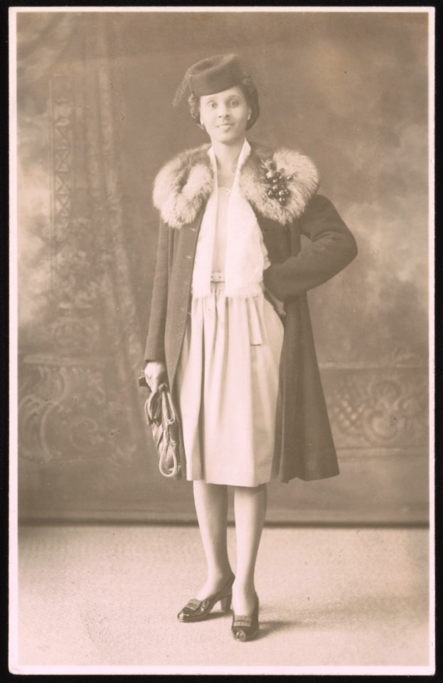 Roxanna Cogburn Davis, hand on hip, wearing fur collard coat and hat, full-length studio portrait, facing front LCCN2015650012