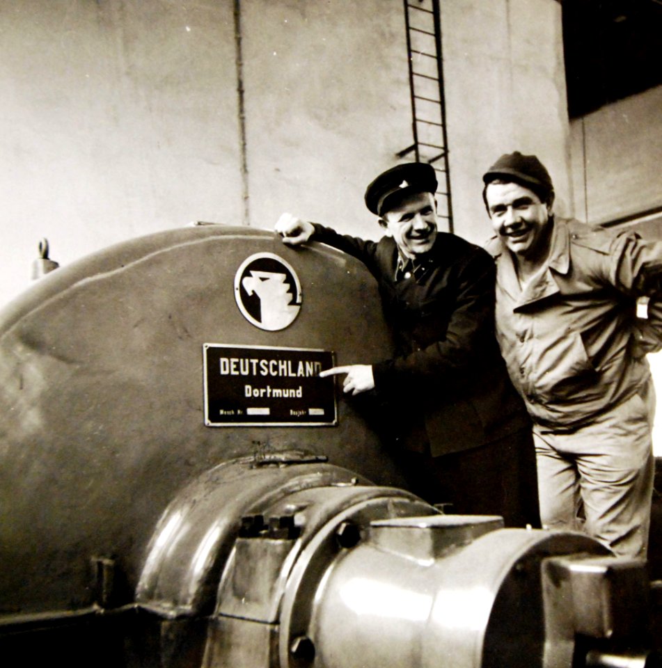 Russian railroad engineer pointing at the sign of German-made railroad machinery, 1943 (24767914699)