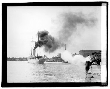 Sailing ship in harbor; smokestack with billowing smoke in background LOC npcc.04043