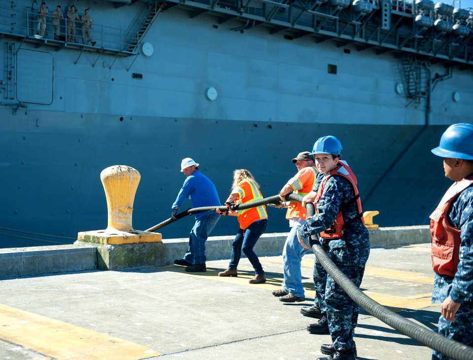 Sailors assigned to the aircraft carrier USS Nimitz (CVN 68) and Navy contractors handle lines as the Wasp-class amphibious assault ship USS Essex (LHD 2) departs from Naval Station Everett 140729-N-FV746-078