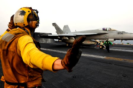 Sailor signals to the pilot of an F A-18E Super Hornet to hold, as another Sailor clears the launch area (5916364228)