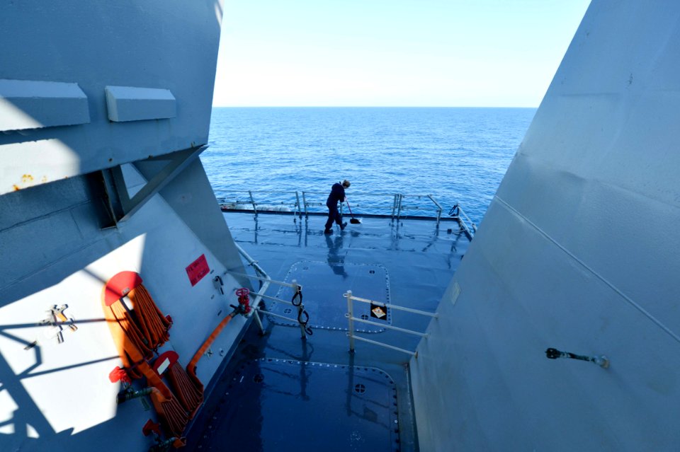 Sailor sweeping during wash down aboard USS Ross (DDG-71) 160203-N-XT273-066