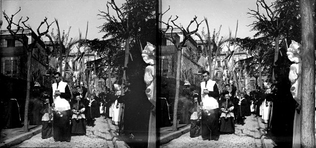 Sacerdot , nens amb palmes i públic a la processó de rams de l'església de la Concepció al carrer Aragó