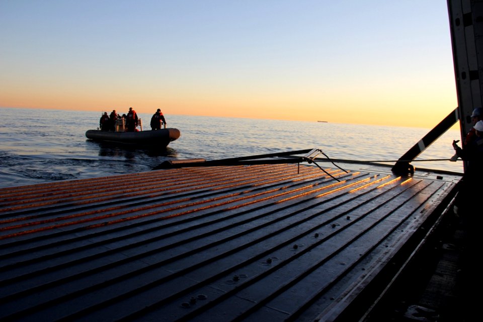 Sailors assigned to the amphibious transport dock ship USS Mesa Verde (LPD 19) tow debris in a rigid-hull inflatable boat (RHIB) from the crash site of MH-53E 140108-N-HB951-375